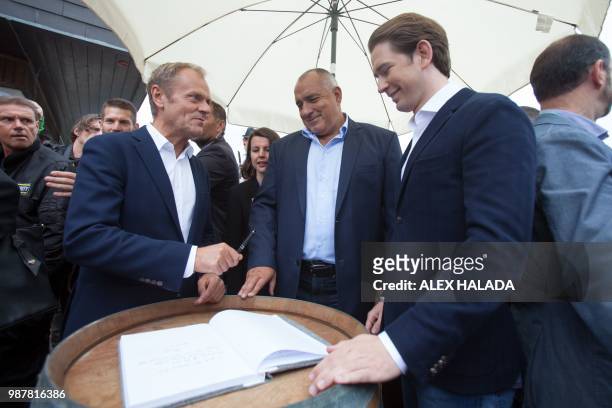 President of the European Council Donald Tusk holds the pencil after signing the mountain Planai summit book in front of the cable car station next...