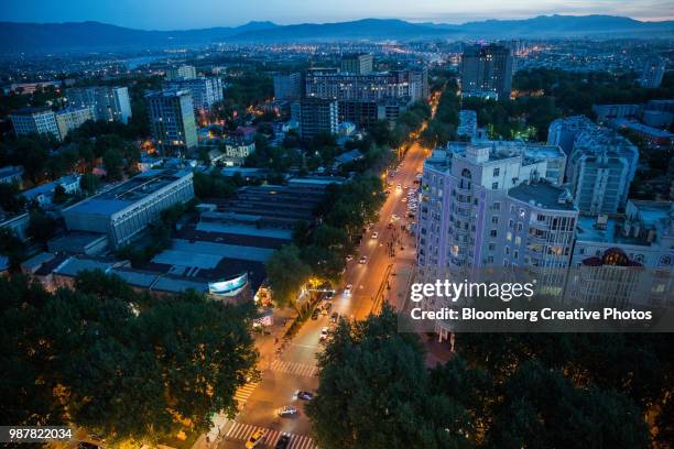 traffic moves along a road as residential and commercial buildings stand in dushanbe - tadjik photos et images de collection