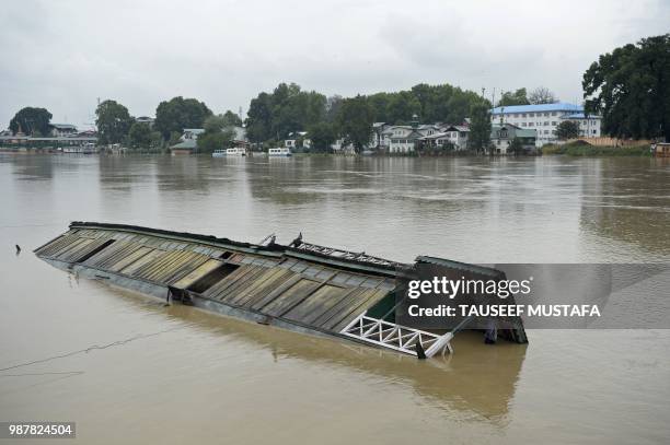 Partially submerged houseboat is seen in Jhelum river after heavy rain in Srinagar on June 30, 2018. - Authorities issued a flood alert in central...