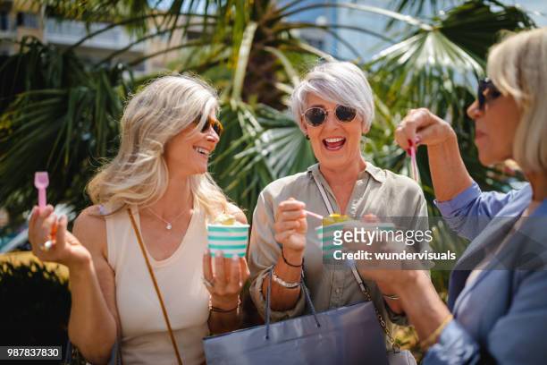 mature women eating ice cream while shopping in the city - group of mature women stock pictures, royalty-free photos & images