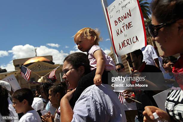 Man holds an Arizona flag as fellow demonstrators protest Arizona's new immigration enforcement law during a May Day rally at the state capitol...