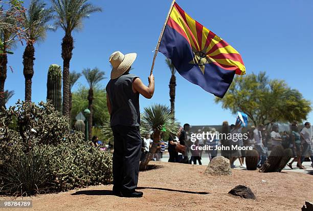 Man holds an Arizona state flag as fellow demonstrators protest Arizona's new immigration enforcement law during a May Day rally at the state capitol...