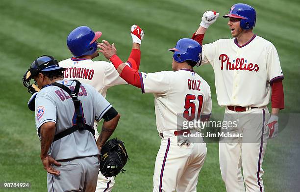 Shane Victorino of the Philadelphia Phillies celebrates his fourth inning three run home run with teammates Carlos Ruiz and Roy Halladay as Henry...