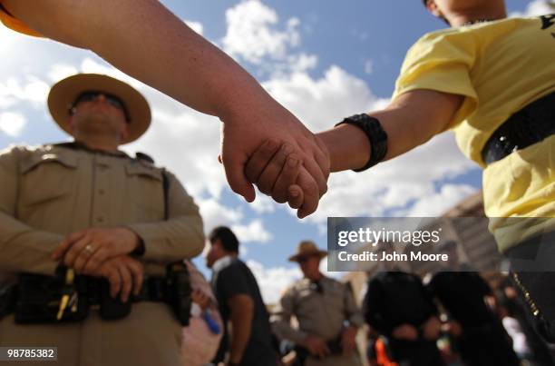 Demonstrators protesting Arizona's new immigration law clasp hands in front of a police line during a May Day rally at the state capitol building on...