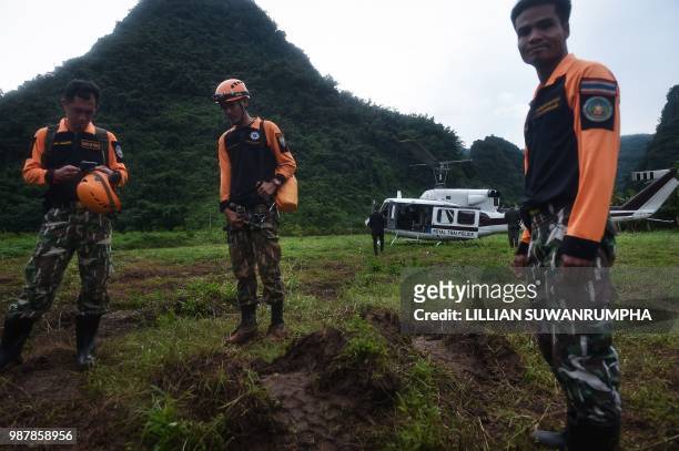 Thai rescue workers wait to get on a helicopter near the Tham Luang cave, at the Khun Nam Nang Non Forest Park in Chiang Rai province on June 30,...