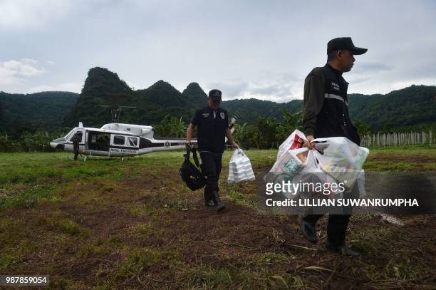 Thai police take supplies from a helicopter near the Tham Luang cave, at the Khun Nam Nang Non Forest Park in Chiang Rai province on June 30, 2018 as...