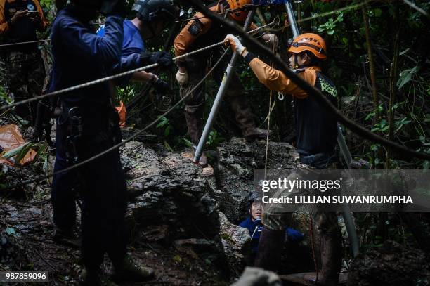 Thai rescue specialists help a Thai Airforce soldier descent into a possible opening to the Tham Luang cave, at the Khun Nam Nang Non Forest Park in...