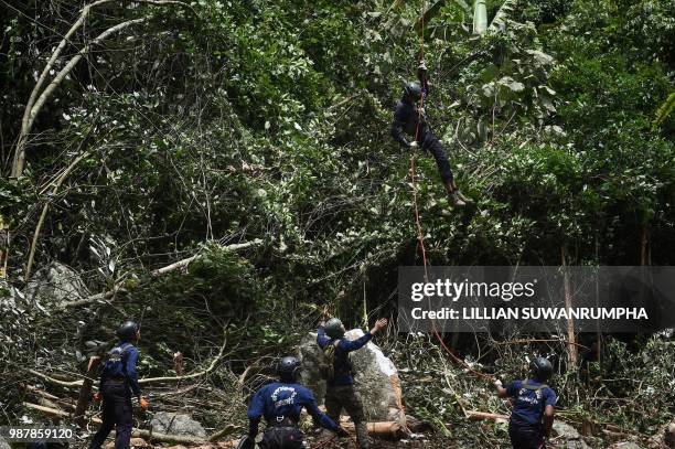 Thai Airforce worker drops in by helicopter into a clearing in the forest near a possible overground opening to the Tham Luang cave, at the Khun Nam...