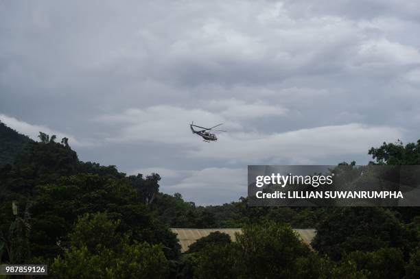 Royal Thai Police helicopter flies near the Tham Luang cave, at the Khun Nam Nang Non Forest Park in Chiang Rai province on June 30, 2018 as the...