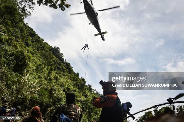 Thai Airforce worker drops in by helicopter into a clearing in the forest near a possible overground opening to the Tham Luang cave, at the Khun Nam...