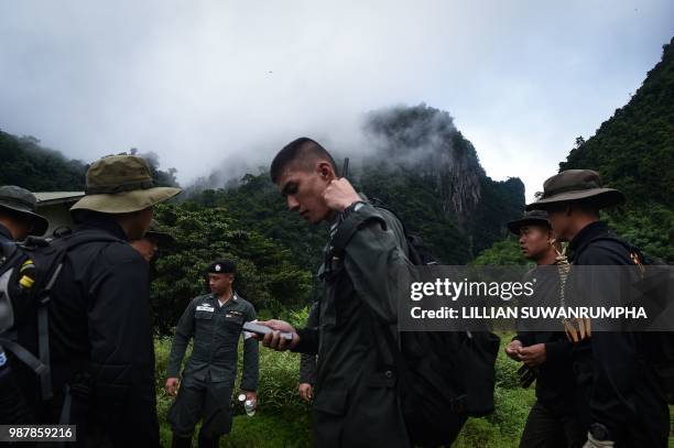 Thai soldiers and police gather in the mountains near the Tham Luang cave at the Khun Nam Nang Non Forest Park in Chiang Rai province on June 30,...