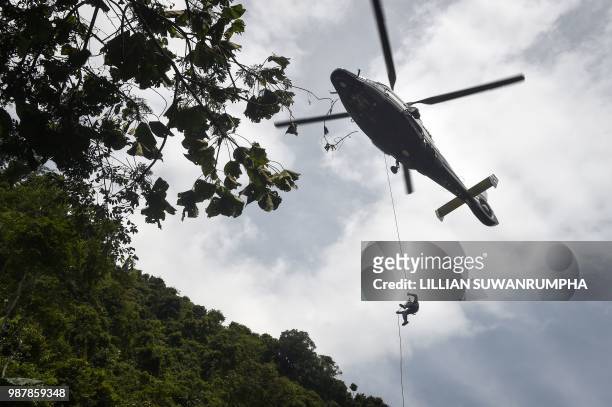 Thai Airforce worker drops in by helicopter into a clearing in the forest near a possible overground opening to the Tham Luang cave, at the Khun Nam...