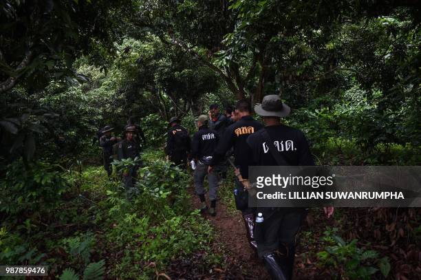 Thai soldiers and police walk into the forest to explore a possible overground opening to Tham Luang cave, at the Khun Nam Nang Non Forest Park in...
