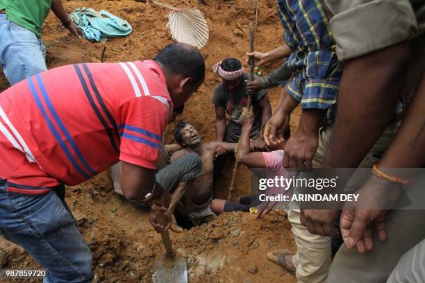 Indian villagers and fire brigade personnel rescue a labourer trapped in the mud after a landslide at a construction site in Agartala, the capital of...