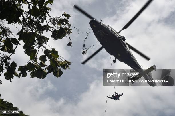 Thai Airforce worker drops in by helicopter into a clearing in the forest near a possible overground opening to the Tham Luang cave, at the Khun Nam...