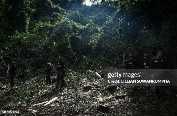 Thai soldiers and police stand in a clearing in the forest made for helicopter landings near Tham Luang cave at the Khun Nam Nang Non Forest Park in...