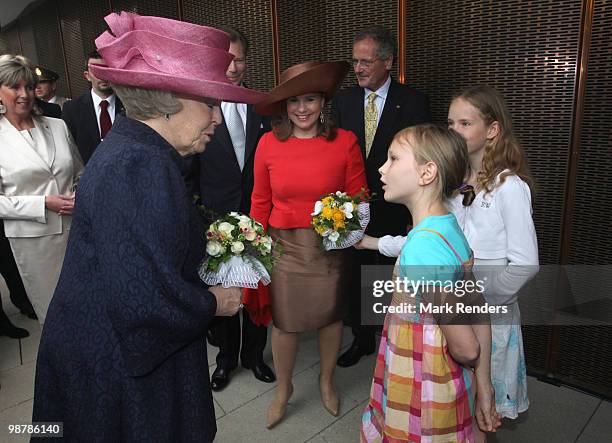 Queen Beatrix of the Netherlands receives flowers from a Dutch girl as she attends the inauguration exhibition 'The Golden Age Reloaded' following...