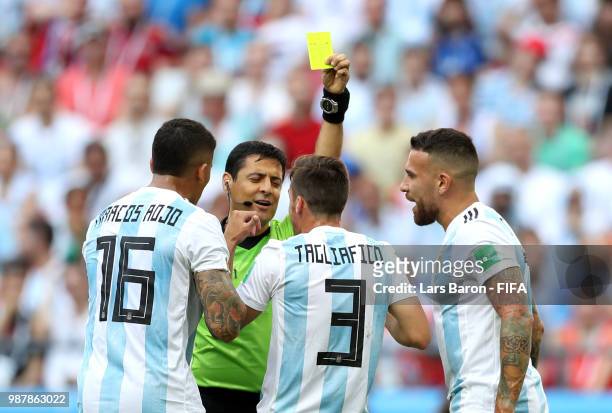 Marcos Rojo of Argentina is shown a yellow card by referee Alireza Faghani, whilst team mates Nicolas Tagliafico and Nicolas Otamendi of Argentina...