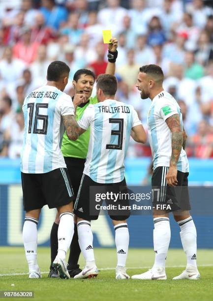 Marcos Rojo of Argentina is shown a yellow card by referee Alireza Faghani, whilst team mates Nicolas Tagliafico and Nicolas Otamendi of Argentina...