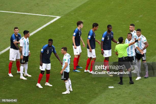 Paul Pogba of France and Gabriel Mercado of Argentina speak with match referee Alireza Faghani as players prepare for a free kick to be taken during...