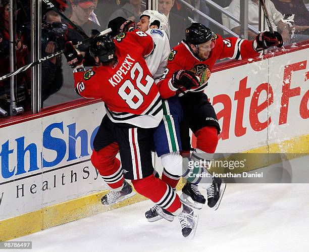 Tomas Kopecky and Kris Versteeg of the Chicago Blackhawks combine to check Kevin Bieksa of the Vancouver Canucks in Game One of the Western...