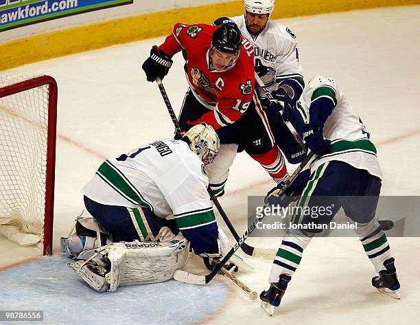 Roberto Luongo of the Vancouver Canucks stop a shot by Jonathan Toews of the Chicago Blackhawks with assistance from teammates Andrew Alberts and...