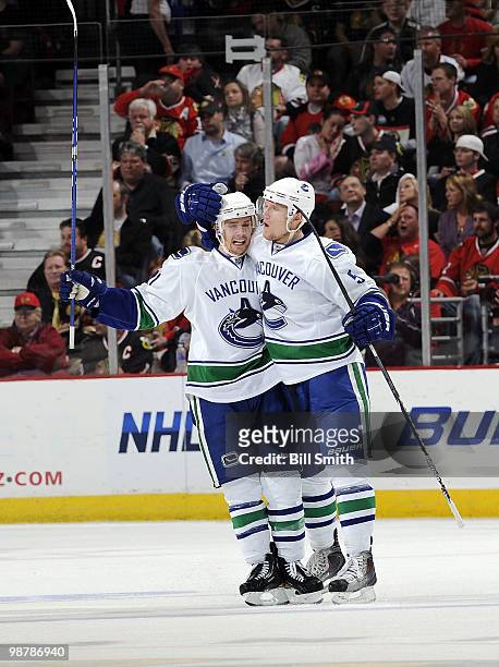 Christian Ehrhoff of the Vancouver Canucks celebrates with teammate Mason Raymond after scoring against the Chicago Blackhawks at Game One of the...
