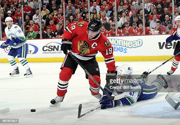 Jonathan Toews of the Chicago Blackhawks approaches the puck as Andrew Alberts of the Vancouver Canucks reaches from down on the ice at Game One of...