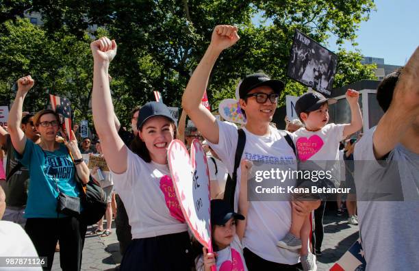 Maia Leung and family rise their hands as they attend the nationwide "Families Belong Together" march on June 30, 2018 in New York City. As thousands...