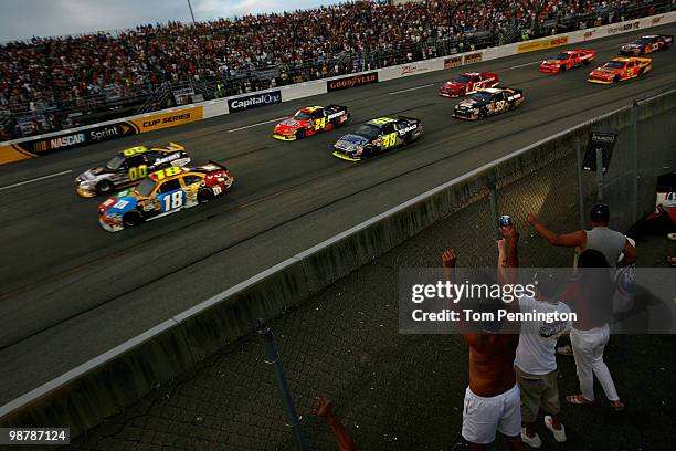 Race fans cheer as Kyle Busch , driver of the M&M's Toyota and David Reutimann, driver of the Aaron's Dream Machine Toyota, lead the field at the...