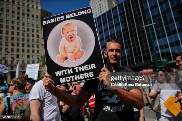 Man holds a poster as he attends the nationwide "Families Belong Together" march on June 30, 2018 in New York City. As thousands of migrant children...