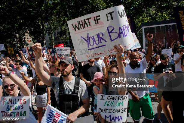 Family hold signs as they attend the nationwide "Families Belong Together" march on June 30, 2018 in New York City. As thousands of migrant children...