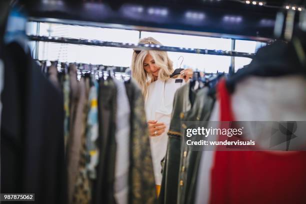 reife frau mit grauen haaren, die wahl der kleidung im bekleidungsgeschäft - kaufsucht stock-fotos und bilder