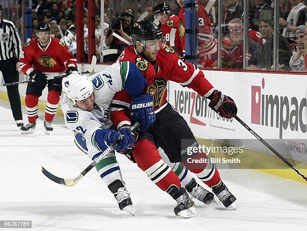 Kris Versteeg of the Chicago Blackhawks reaches for the puck as Kyle Wellwood of the Vancouver Cancucks pushes from behind at Game One of the Western...