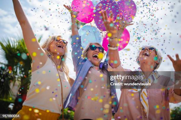 upphetsad mogna kvinnor firar med färgglada konfetti och ballonger utomhus - party balloons bildbanksfoton och bilder