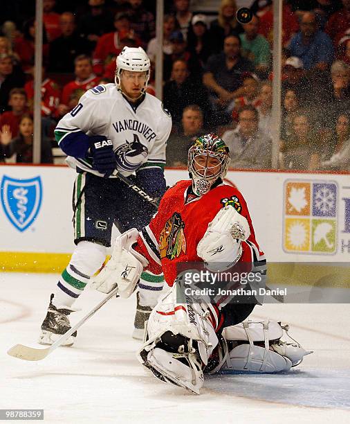 Cristobal Huet of the Chicago Blackhawks knocks the puck in the air as Michael Grabner of the Vancouver Canucks watches in Game One of the Western...