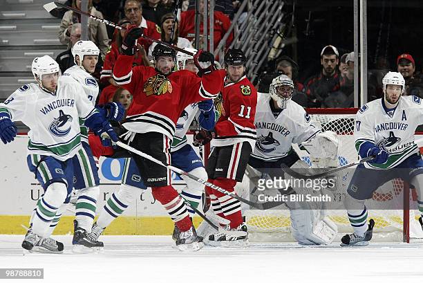 Troy Brouwer and John Madden of the Blackhawks wait in position in front of Vancouver Canucks goalie Roberto Luongo with Steve Bernier, Kevin Bieksa...