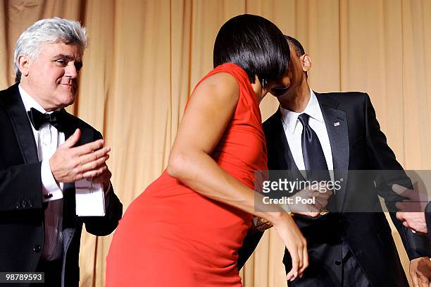 President Barack Obama kisses the First Lady Michelle Obama as comedian Jay Leno looks on during the White House Correspondents' Association Dinner...