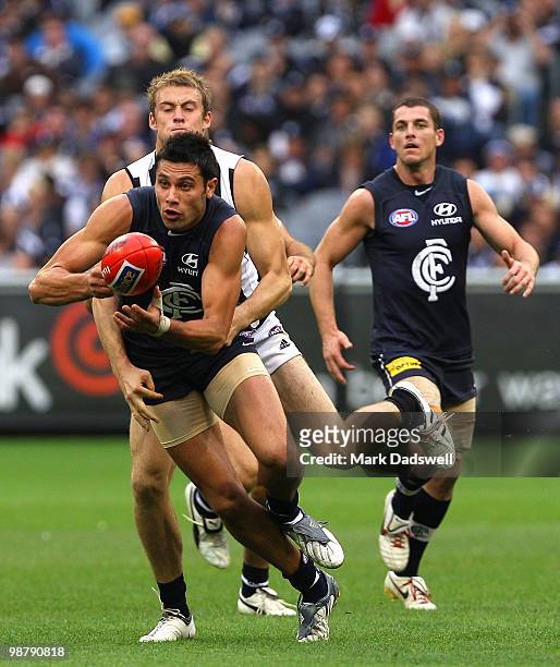 Setanta O'hAilpin of the Blues handballs as he is tackled during the round six AFL match between the Carlton Blues and the Collingwood Magpies at...