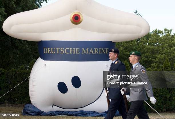 June 2018, Germany, Berlin: Soldiers of the German Bundeswehr pass an advertising display of the marines on open house day at the German Bundeswehr...