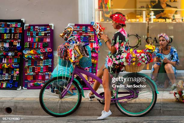 Colombian street vendors show off colorful fashion accessories on the sidewalk in the colonial walled city on April 16, 2018 in Cartagena, Colombia....