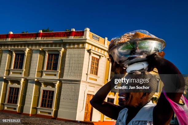 An Afro-Colombian street vendor carries on her head a bowl full of sweet homemade candies in the colonial walled city on December 15, 2017 in...