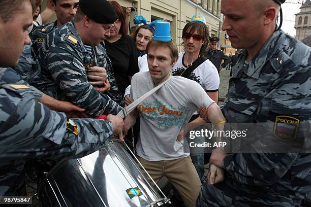 Russian riot police arrest an activist with an item on his head imitating a car flasher installed on cars of Russian officials during a rally in...