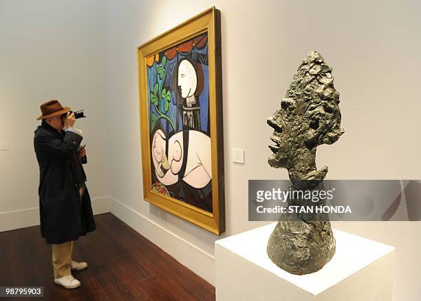 By PAOLA MESSANA A man photographs Pablo Picasso's "Nude, Green Leaves and Bust" estimated at USD 70 million to 90 million next to Alberto...