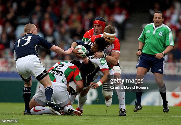 Lifeimi Mafi of Munster is tackled by Benoit August and Imanol Harinordoquy during the Heineken Cup semi final match between Biarritz Olympique and...