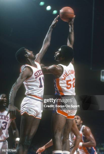 Buck Williams of the New Jersey Nets shoots over Caldwell Jones of the Philadelphia 76ers during an NBA basketball game circa 1982 at The Spectrum in...