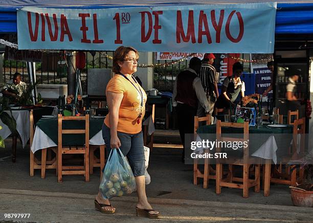 Cuban passes by a banner hailing May Day, in Havana May 2, 2010. CTC union leader Salvador Valdes asked the Cuban people "extraordinary efforts and...