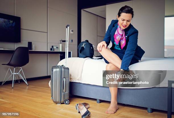 cabin crew member is massaging her tired feet after long flight - beautiful long legs imagens e fotografias de stock