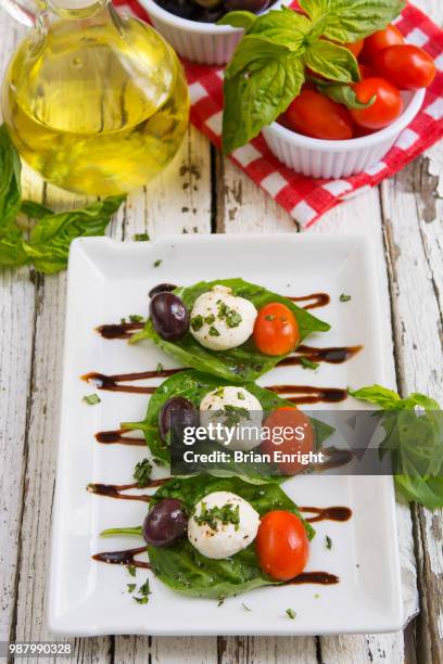 caprese salad with olive oil and balsamic vinegar on a white plate and a rustic wooden table - white vinegar stock pictures, royalty-free photos & images