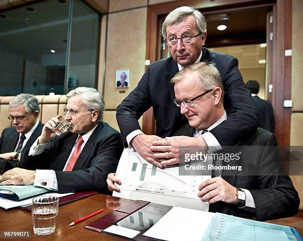 Jean-Claude Juncker, Luxembourg's prime minister and president of the Eurogroup, rear, covers a chart held by Olli Rehn, European Union economic and...